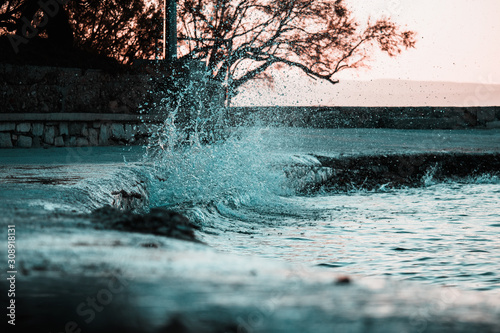 Sea water waves hitting the shore, dramatic scene of water captured in the air. Cold winter morning in split,croatia. Water splashing the pathway