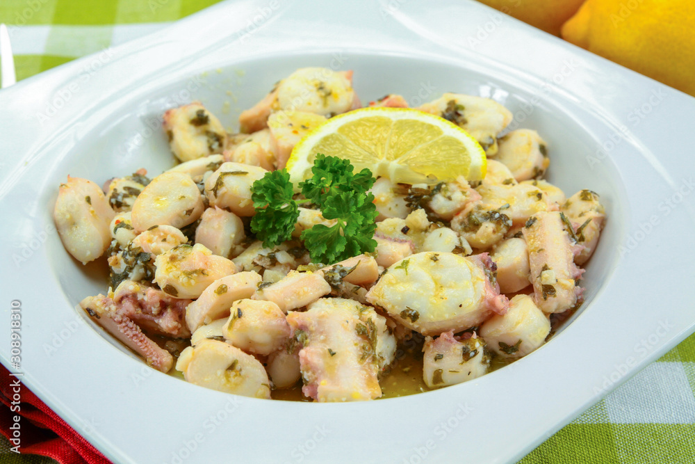 Octopus pieces cooked with garlic and parsley on a plate Octopus pieces cooked with garlic and parsley on a plate