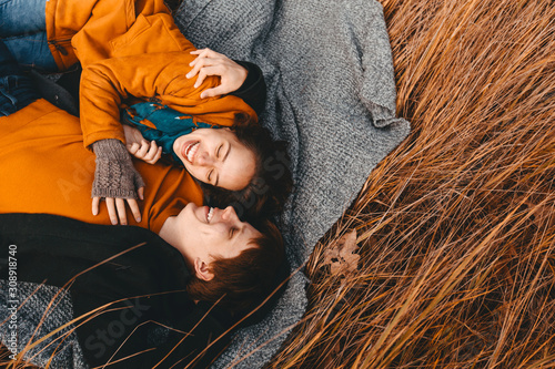 Young man and woman are lying and hugging in the autumn field.