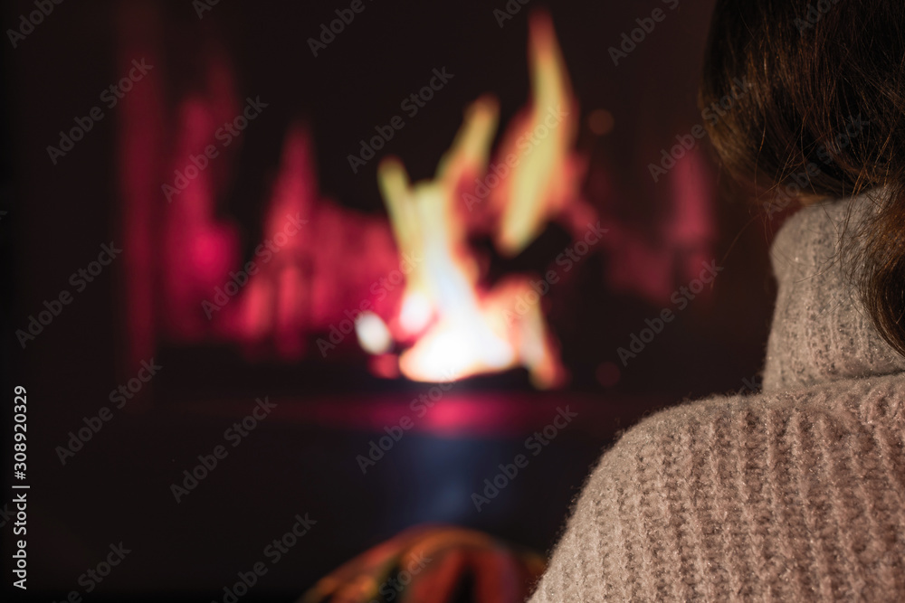 Woman in a winter sweater sitting near Christmas fireplace. Winter and Christmas holidays concept