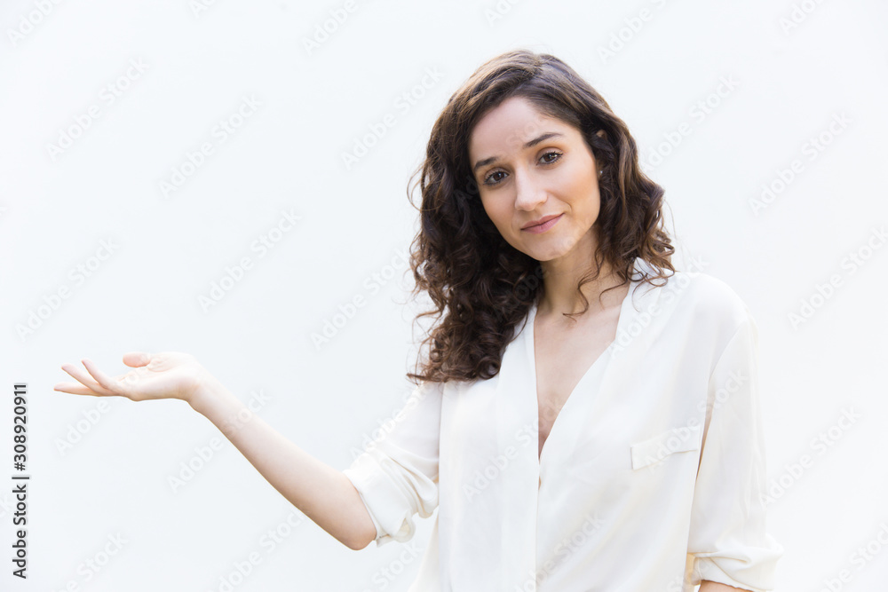 Positive beautiful student girt showing empty copy space. Wavy haired young woman in casual shirt standing isolated over white background. Advertising concept Positive beautiful student girt showing empty copy space. Wavy haired young woman in casual shirt standing isolated over white background. Advertising concept