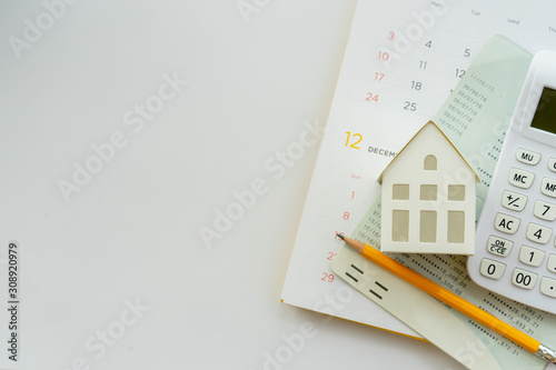close up top view group of calculator , home model ,yellow pencil, banking account book and calendar on white color background with space for money management ,home loan and personal financial concept photo