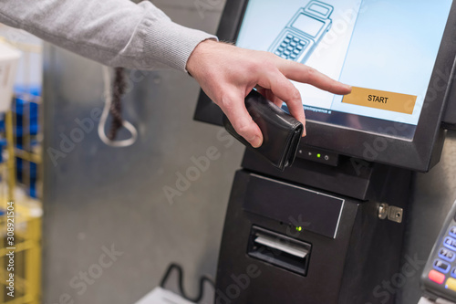 Man paying at the self-service counter using the touchscreen display and credit card. Isometric self-service cashier or terminal. photo