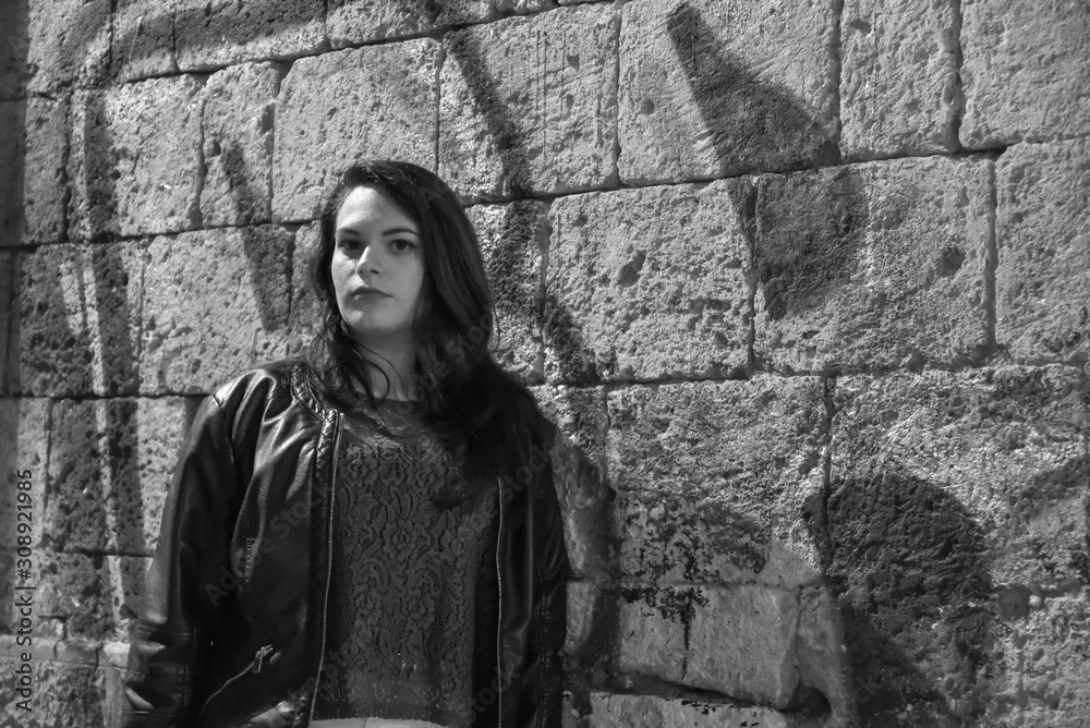 Portrait of Young Beautiful Woman Near the Wall by Night in the City