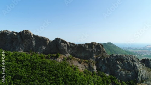 Breathtaking aerial view of the green hill and the valley on blue sky background. Shot. Flying above the small town and green mountains. photo