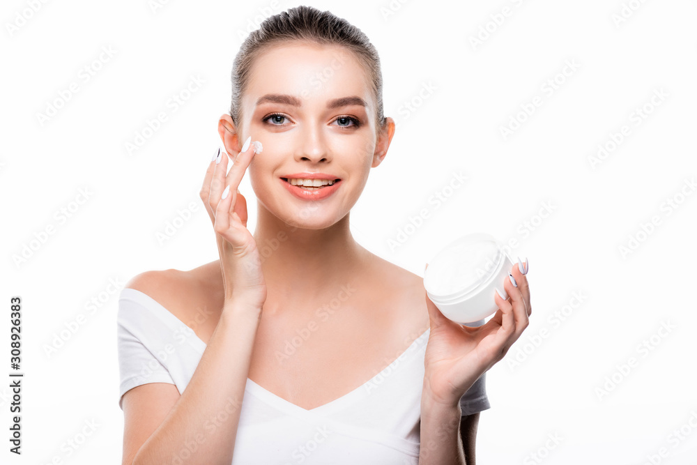 attractive, smiling woman applying face cream and looking at camera isolated on white attractive, smiling woman applying face cream and looking at camera isolated on white