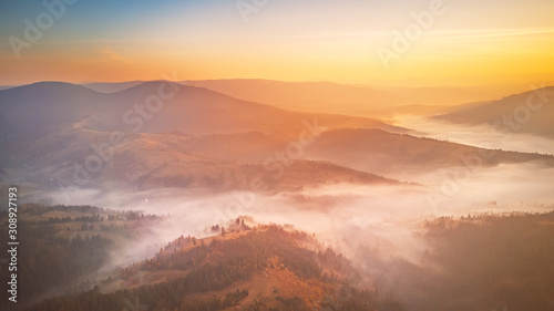 Sunrise over mountain foggy valley. Misty woodland in the morning
