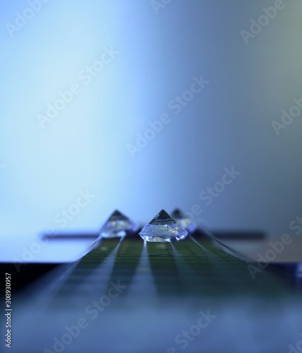 Glass diamonds lie on the guitar strings on the guitar neck
