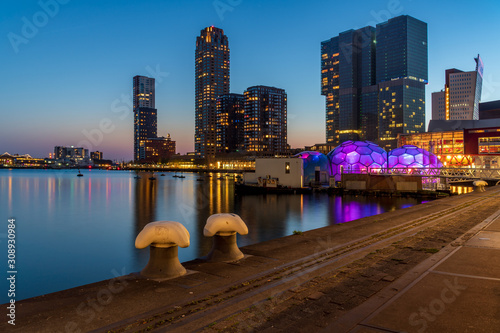 Rijnhaven Rotterdam, the Netherlands, Skyline with Kop van Zuid as seen from Posthumalaan. Cityscape with skyscrapers on the Wilhelminapier and a colourful floating pavilion during blue hour.