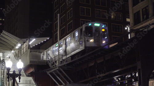 Quadro em tela Night time exterior of loop train passing through elevated station on tracks thr