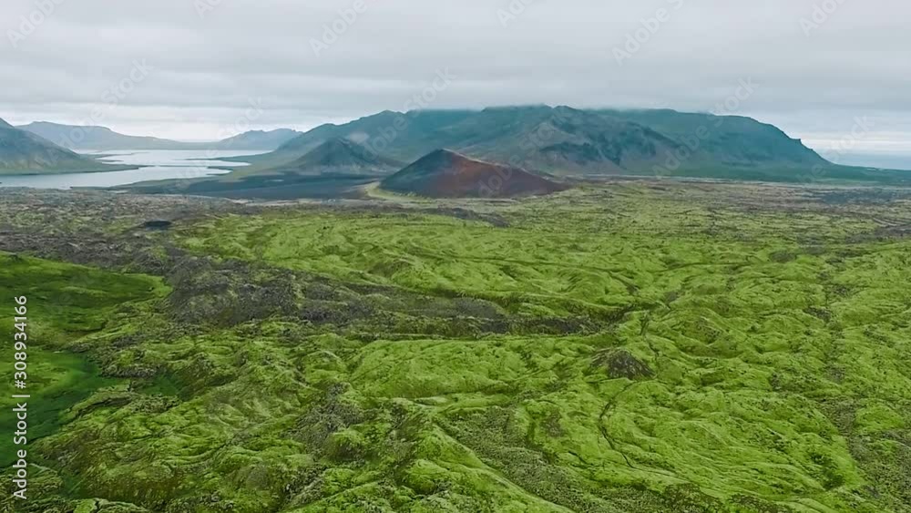 Slow forward aerial of green mountain crater landscape beside lake and mountain,Iceland Slow forward aerial of green mountain crater landscape beside lake and mountain,Iceland