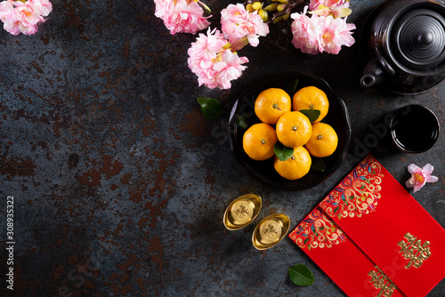 Chinese new year festival decorations pow or red packet, orange and gold ingots or golden lump on a black stone texture background. Chinese characters FU means fortune good luck, wealth, money flow.