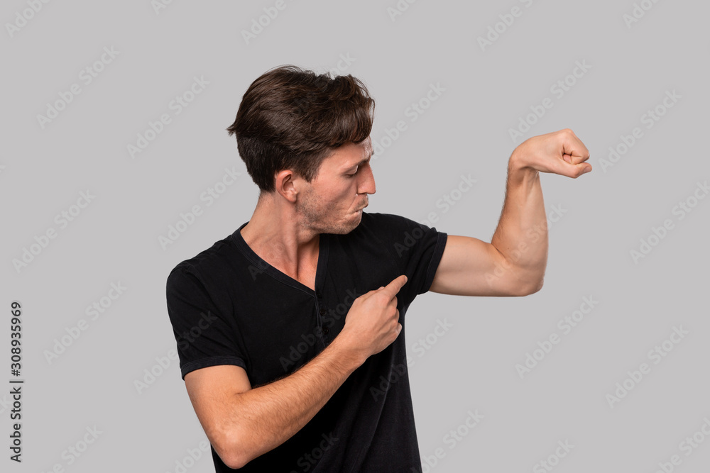 Handsome man pointing at his muscle bicep.
