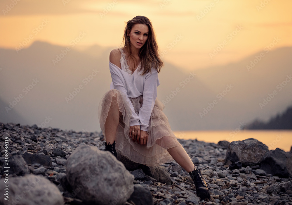 Fashionable female model in stylish outfit posing over mountain view