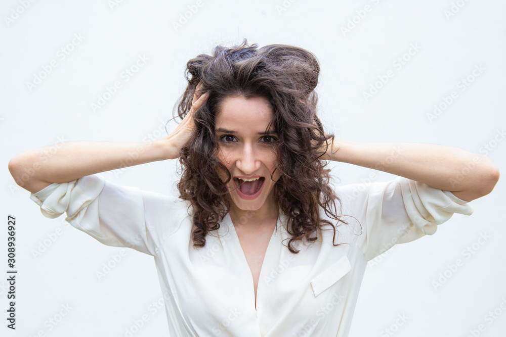 Happy amazed student girl gasping or shouting for joy, holding head. Wavy haired young woman in casual shirt standing isolated over white background. Surprise or joy concept Happy amazed student girl gasping or shouting for joy, holding head. Wavy haired young woman in casual shirt standing isolated over white background. Surprise or joy concept