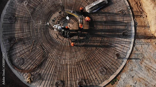 Builders make a foundation of metal fittings under a wind generator. Aerial