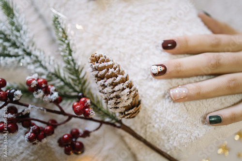 Girl's hands with Holiday manicure and pine branch