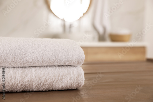 Stack of clean towels on wooden table in bathroom. Space for text