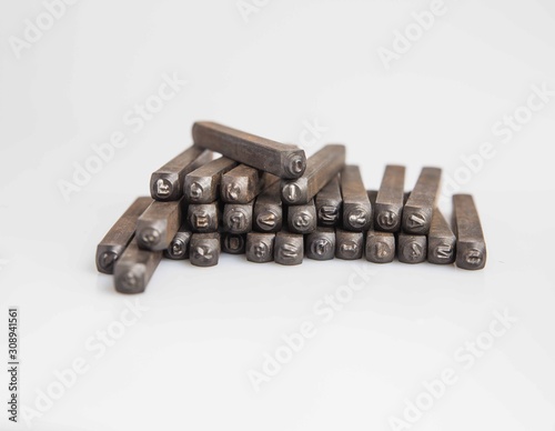 London, England, 29/11/19 vintage retro old school aged wooden box full of a set of alphabetical and numerical steel punches made of strong metal for industrial production shot on white background