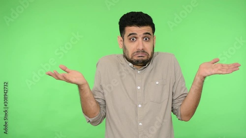I don't know. Confused brunette man with bristle in shirt shrugging shoulders making questioning gesture, looking uncertain doubtful about answer. indoor studio shot, green background, chroma key