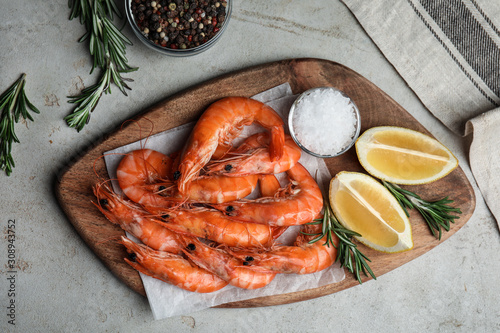 Fototapeta Naklejka Na Ścianę i Meble -  Delicious cooked shrimps served with rosemary and lemon on grey table, flat lay