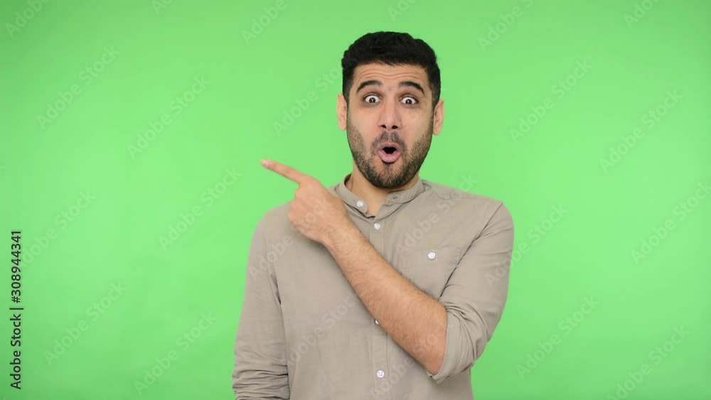 Wow, look here! Amazed man in shirt pointing copy space and nodding approvingly, looking shocked surprised, showing advertising area for promotional text or product. indoor studio shot, chroma key Wow, look here! Amazed man in shirt pointing copy space and nodding approvingly, looking shocked surprised, showing advertising area for promotional text or product. indoor studio shot, chroma key