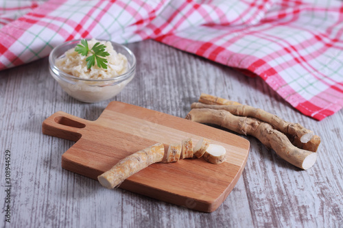 The process of making spicy horseradish sauce. Horseradish root on a cutting board