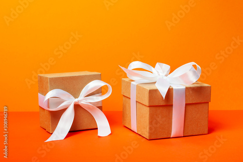 Trendy attractive minimalistic gifts on the orange background. Merry Christmas, St. Valentine's Day, Happy Birthday and other holidays concept.