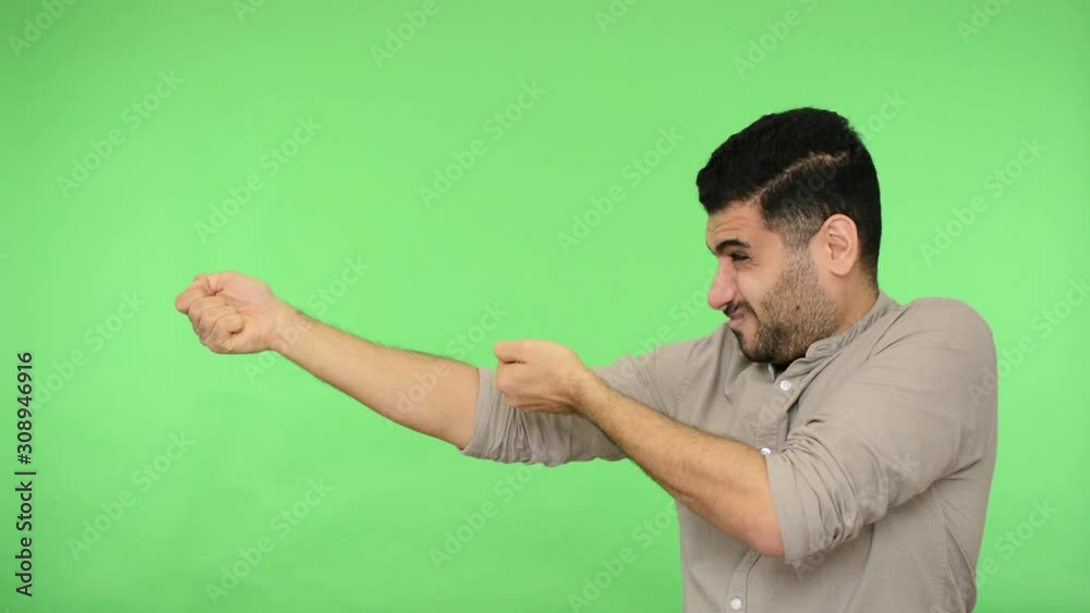 Persistent brunette man in shirt with rolled up sleeves pulling virtual rope, holding heavy invisible object with expression of great effort, empty space. studio shot, green background, chroma key Persistent brunette man in shirt with rolled up sleeves pulling virtual rope, holding heavy invisible object with expression of great effort, empty space. studio shot, green background, chroma key