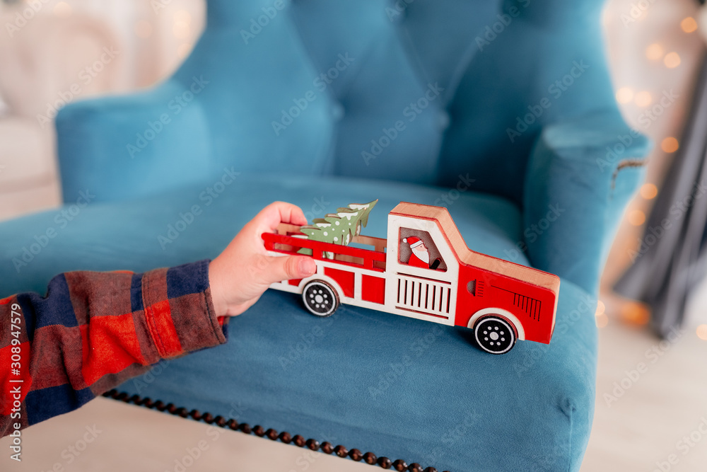 Naklejka premium children's hand holds a toy car with a Christmas tree