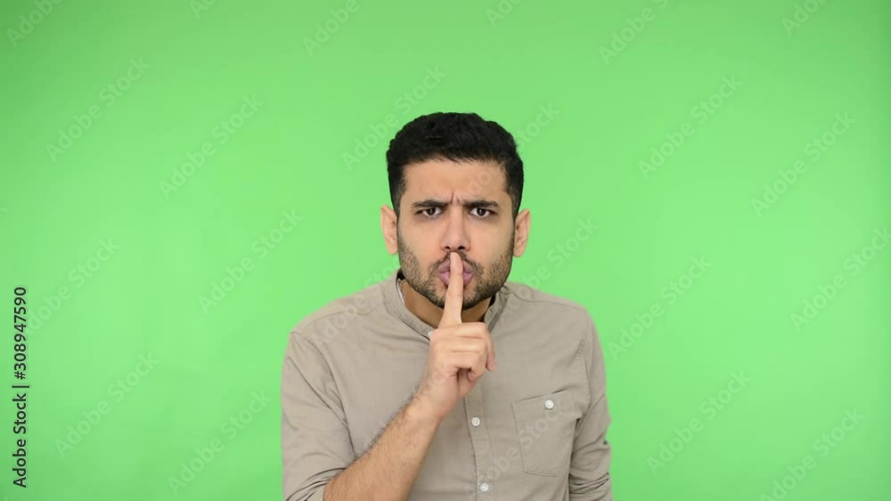 Please, be quiet, keep silent. Strict brunette man with bristle in shirt making silence gesture with finger on his lips, looking serious dissatisfied. indoor studio shot, green background, chroma key