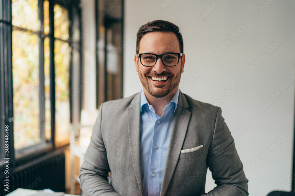 Portrait of young businessman standing in his off - obrazy, fototapety, plakaty 