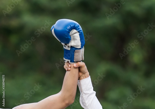 Raising a hand is the winner of a male boxer on a boxing ring.