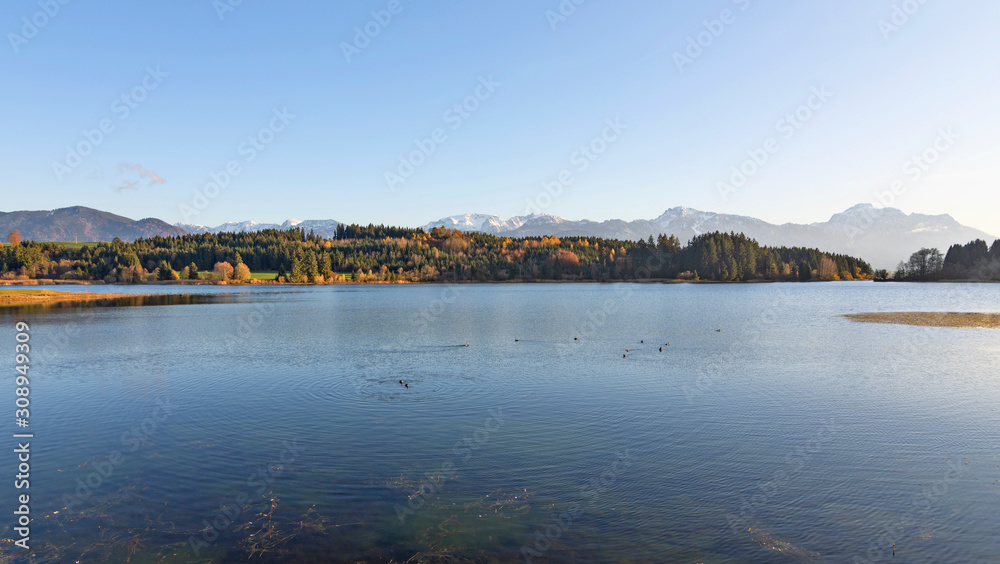 Beautiful lake Illasbergsee in the alpine uplands of the Allgau region (Bavaria, Germany). Forest and snow-covered mountains in the background. Copy space Beautiful lake Illasbergsee in the alpine uplands of the Allgau region (Bavaria, Germany). Forest and snow-covered mountains in the background. Copy space