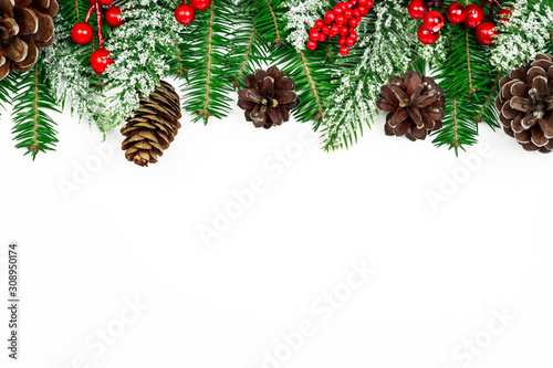 Christmas banner. New Year holidays background. Snowy fir branches, pine cones and red Holly Berries on white background. Christmas and New Year top view decoration with copy space. Part of set.