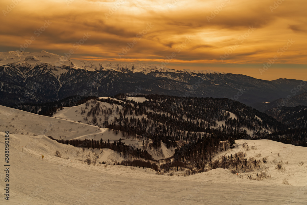 Bright color of sunset sky in Caucasus mountains. Alpine ski resort Krasnaya Polyana in Russia. Beautiful view at winter evening.