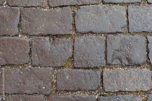 Texture of stone pavement with small crumbs of ice hail. Rugged old cobblestones of the road, stone pavement. Background texture backdrop structure gray