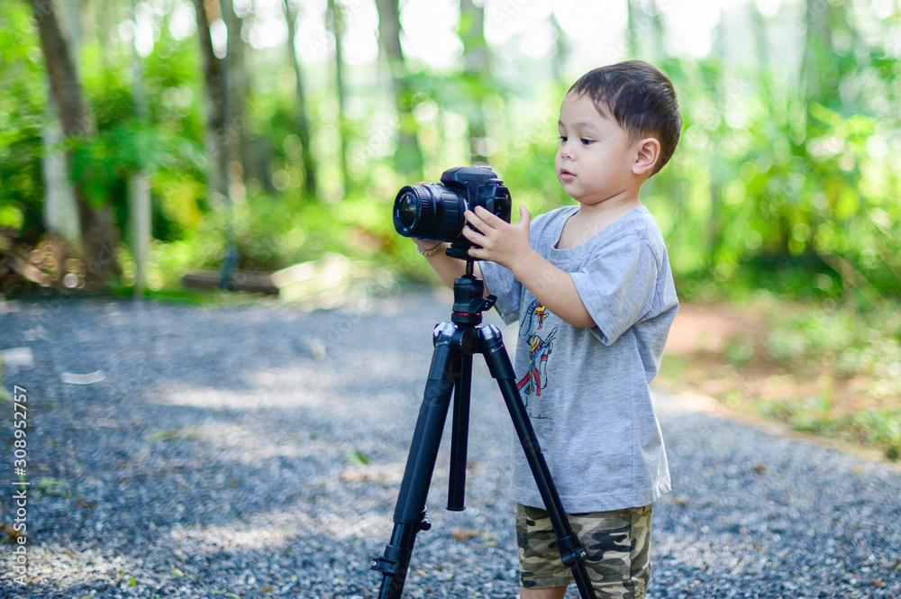  boy is photographer holds a camera on tripod and takes photo 