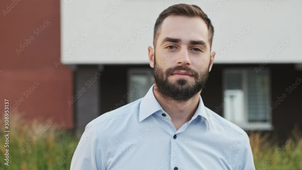 Cool pleased bearded businessman looking at the camera and posing outdoors Cool pleased bearded businessman looking at the camera and posing outdoors