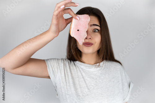 young beautiful woman holding slice of ham near her face loking hungry isolated white background