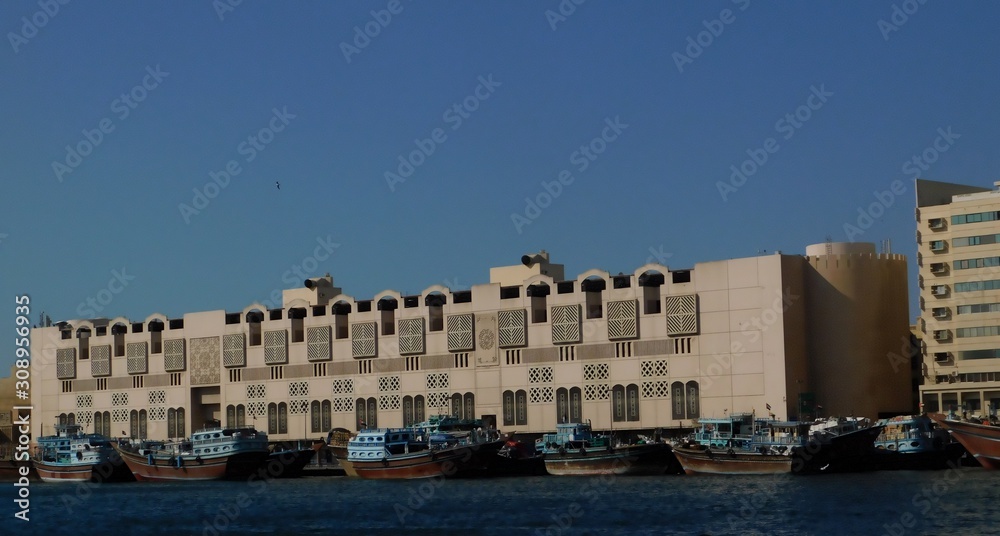 Fishing boats at the pier  in the gulf of the sea on the background of a large building  in the Arabic style, Dubai city