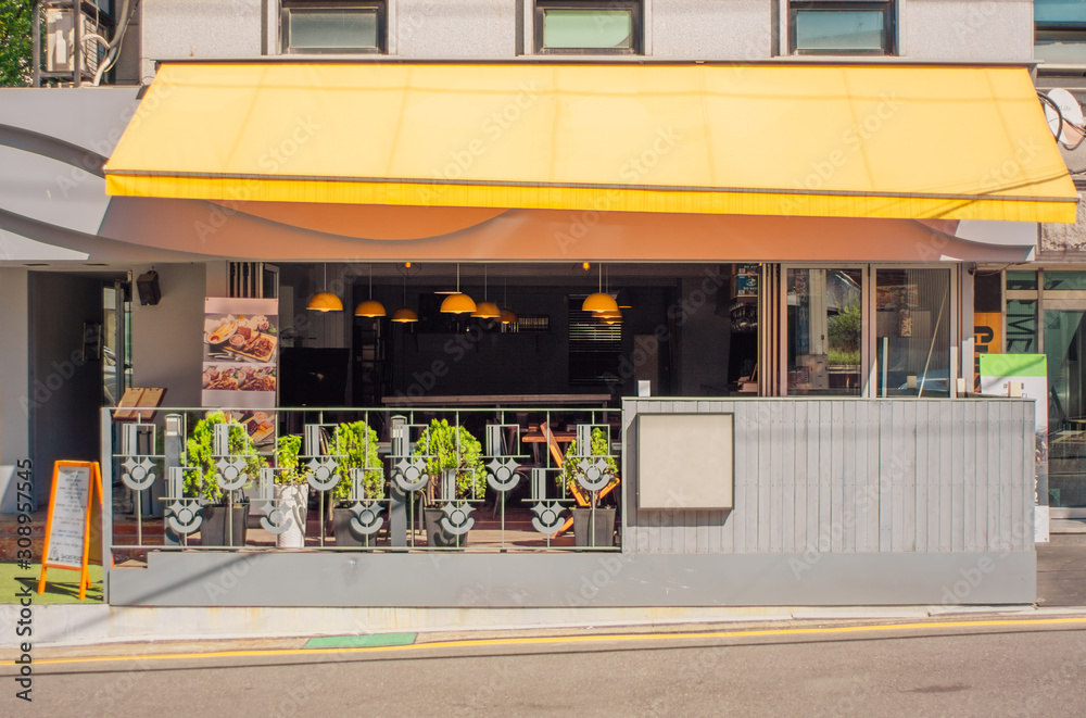 A cafe with yellow sunshade are opened windows on a fine day. A cafe with yellow sunshade are opened windows on a fine day.