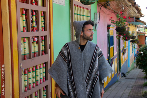 Murais de parede Man with poncho walking on a colorful main street, Marinilla