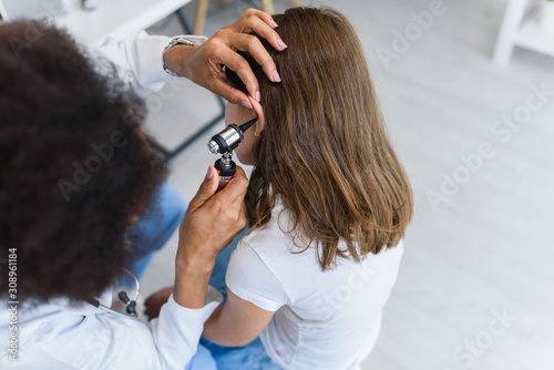 Woman afro american doctor general practitioner examining ear of a ill child. Ear infections.