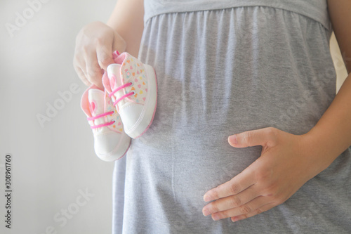 Pregnant woman with little baby shoes