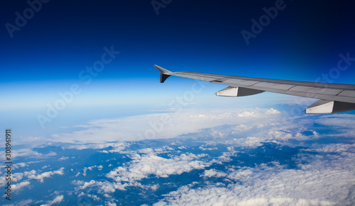 Wing of airplane over white clouds