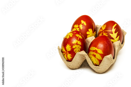 Obraz na płótnie Easter eggs dyed with onion husks with a pattern of fresh leaves of plants on a white background. Creative decoration and DIY concept. Closeup. Postcard with copy space w salonie