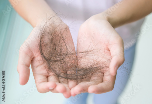 Canvas Print Close-up of woman hand in white t-shirt hold loss hair, after taking shower, concepts of loosing hair or breast cancer