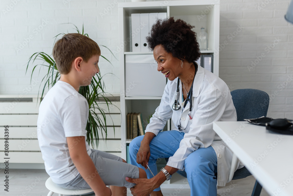 © lordn - Woman African American doctor general practitioner examining child's patellar knee-jerk reflex © lordn - Woman African American doctor general practitioner examining child's patellar knee-jerk reflex