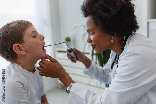 Woman  doctor general practitioner examining child's sore throat photo